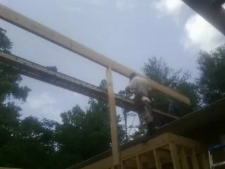 Carpenter setting a ridge beam over a new addition frame — Ice Dam Removal by Roofing Brothers in Port Murray