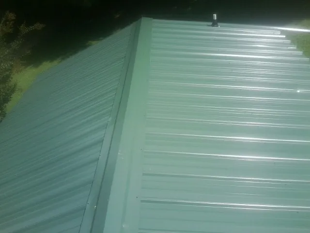 New green metal panels meeting at the ridge of a roof — Flat Roof Repair work by our crew in Port Murray