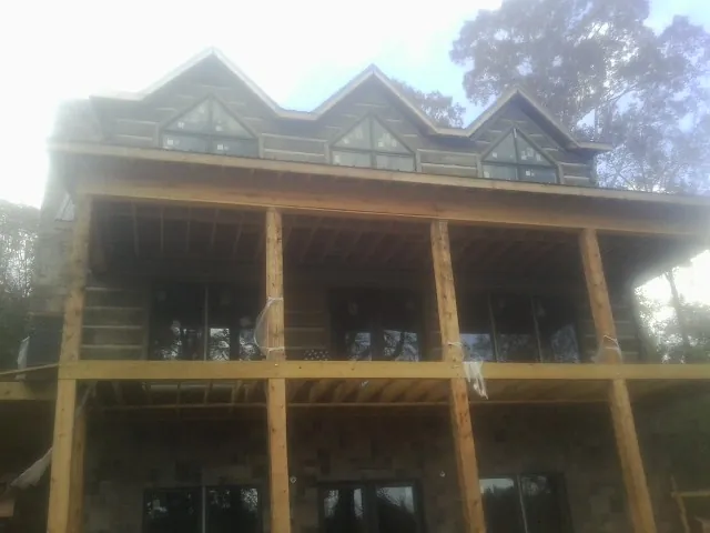 Dormers and porch framing on a large log home under construction — Roof Coating work by our crew in Port Murray