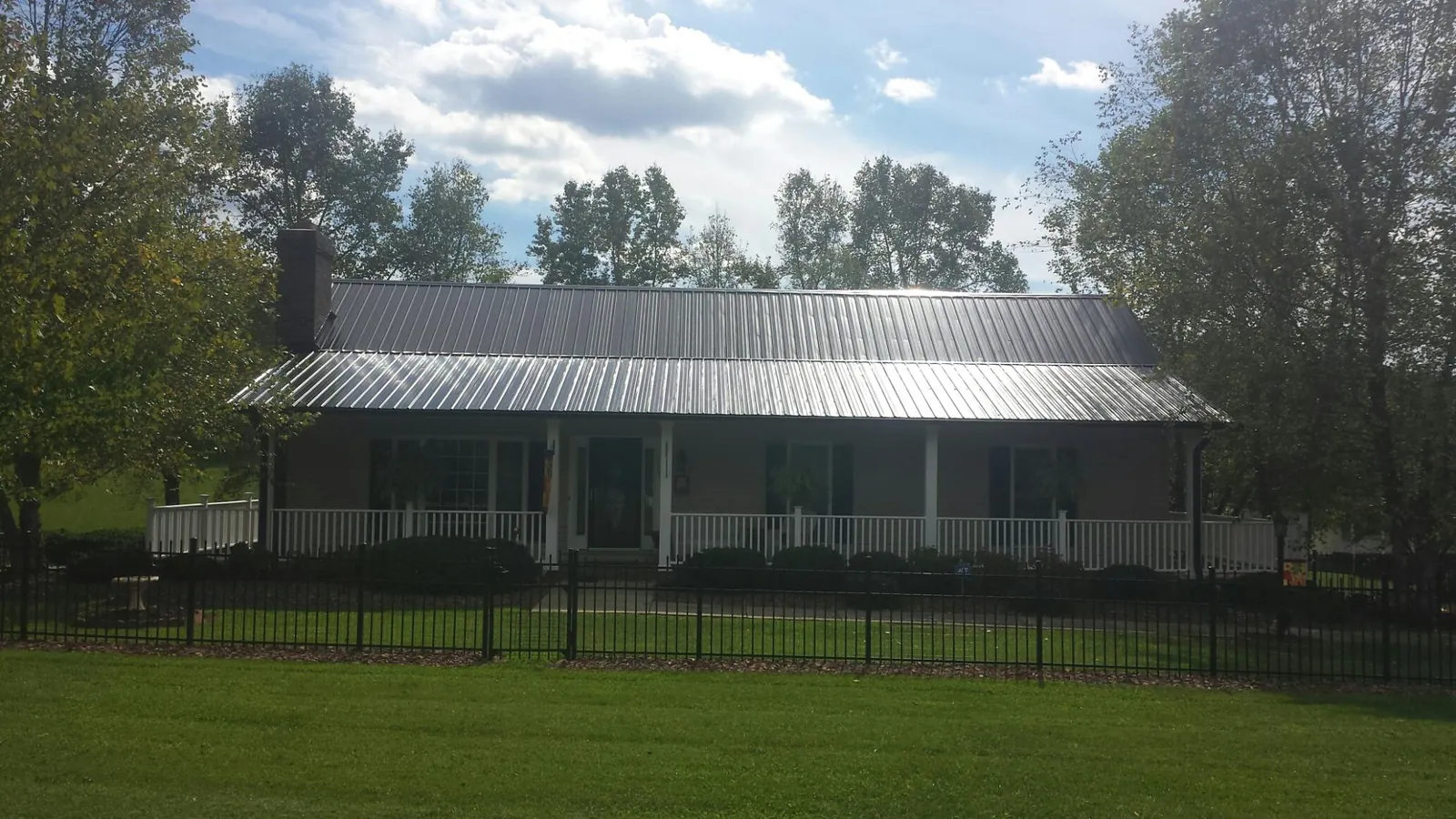 Gray metal roof on a brick ranch with a full width front porch — Gutter Guard Installation work by our crew in Port Murray