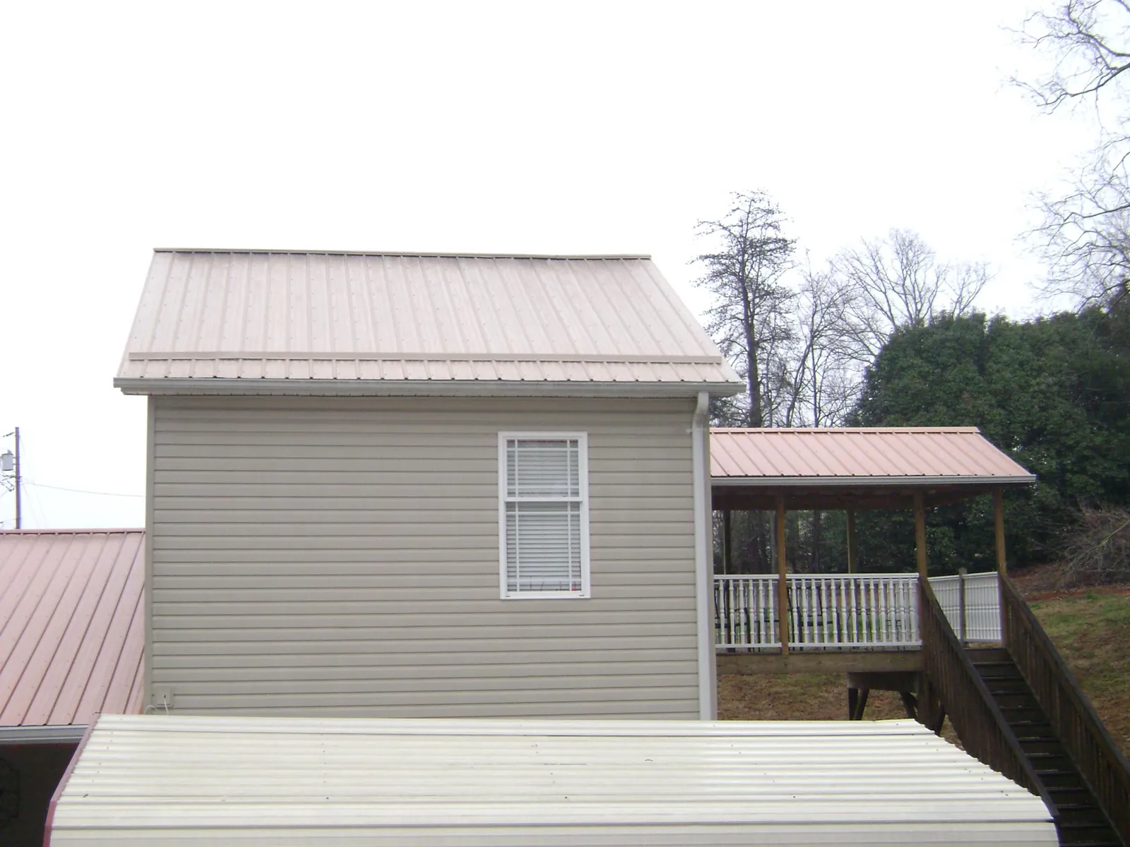 Tan metal roofs on a two story addition and attached porch, from a Roof Replacement job in Port Murray